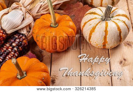 Happy Thanksgiving Text With A Group Of Mini Pumpkins And Indian Corn On A Rustic Wooden Table