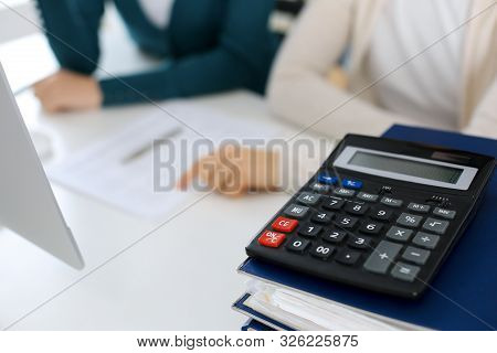 Calculator And Binders With Papers Are Waiting To Be Processed By Business Woman Or Bookkeeper Worki