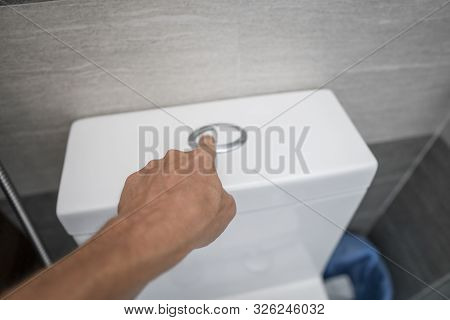 Close Up Of Finger Pushing A Flush Toilet Button For Cleaning A Toilet.