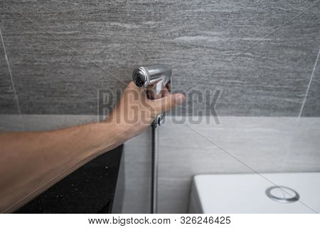 Using Of Bidet Shower In Bathroom With A Bidet Or Toiler. Bidet Shower In Male Hand For Using It In 