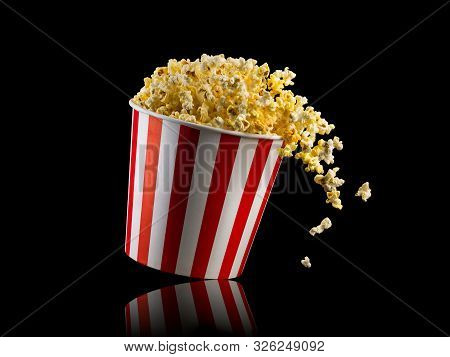 Flying Popcorn From Striped Bucket Isolated On Black Background