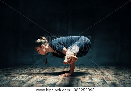 Young Attractive Woman Practicing Yoga Doing Side Crane Pose In Dark Room. Parsva Bakasana Exercise.