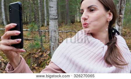A Young Woman Takes Selfie On The Phone With Pleasure In The Spring Forest And Smiles. Slow Mo. Clos