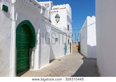 Classic old street in the medina of Asilah with the rampart wall at the end of the street, Northern Morocco