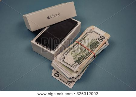 Apple Iphone Devices And Dollars On A Blue Monophonic Background. Voronezh, Russia - May 3, 2019