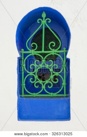 Moroccan colorful design window with a metal railing in Asilah, Morocco