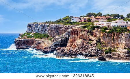 Houses On Cliffs Around Beautiful Beach, Cala Llombards In Mallorca, Turquoise Water And Blue Sky, B