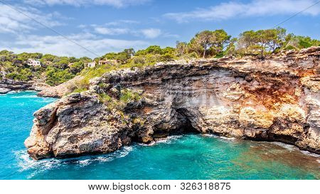 Houses On Cliffs Around Beautiful Beach, Cala Llombards In Mallorca, Turquoise Water And Blue Sky, B