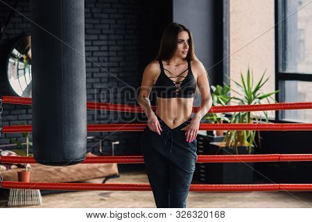 Sexy Fitness Girl In Sportswear Stands Leaned On Ropes Of Boxing Ring.
