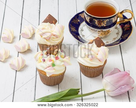 Three Cupcakes Filled With Air Cream And Decorated With Chocolate With Nuts And Candy In The Form Of