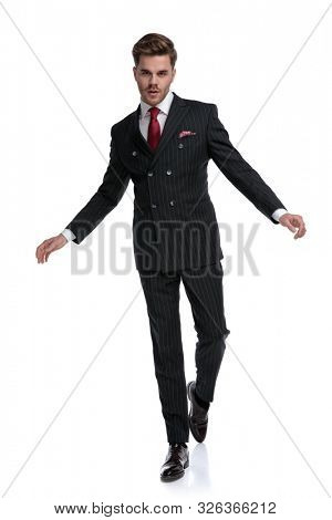 elegant businessman wearing double breasted suit and red tie, walking isolated on white background in studio