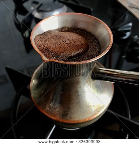Barista Preparing Hot Tasty Drink From Copper Turk, Boils Water For Coffee On Small Fire In Cezve. C