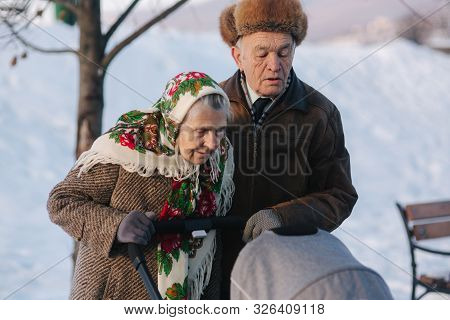 Grand Grandparents Walking With A Baby In Beautiful Pram. Winter Time