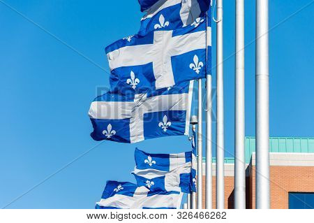 Quebec Flags Waving In The Wind Against Blue Sky In Quebec City.
