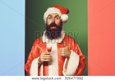 Handsome Bearded Santa Claus Man With Long Beard On Surprisedface Holding Glass Of Alcoholic Shot In
