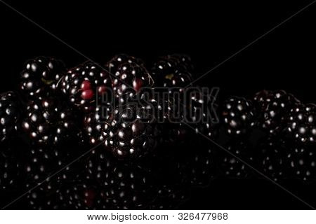 Lot Of Whole Arranged Fresh Black Blackberry Isolated On Black Glass