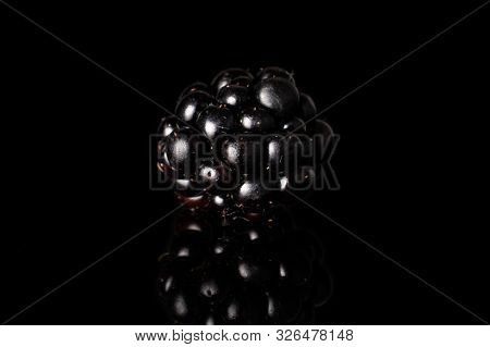 One Whole Fresh Black Blackberry Isolated On Black Glass