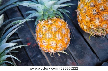 Round Yellow Pineapple On Rustic Wooden Stall. Ripe Pineapple Bunch For Sale On Tropical Farm Market