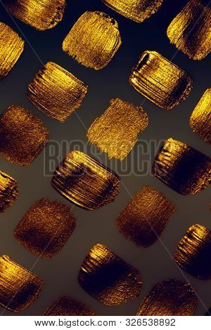 Creative brushstrokes of gold paint isolated on a black background. Gold paint texture.Acrylic gold paint. Smears of cosmetics, blush, highlighter, eye shadow, lipstick.