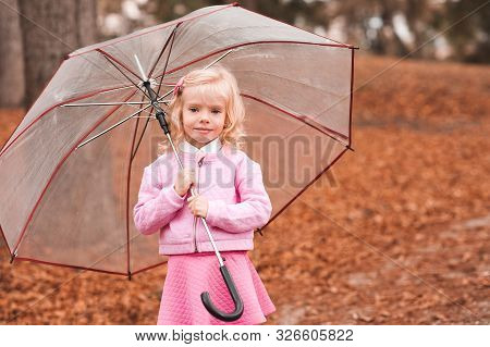 Smiling Blonde Kid Girl 4-5 Yearold Holding Umbrella Standing In Autumn Park Over Nature Background.