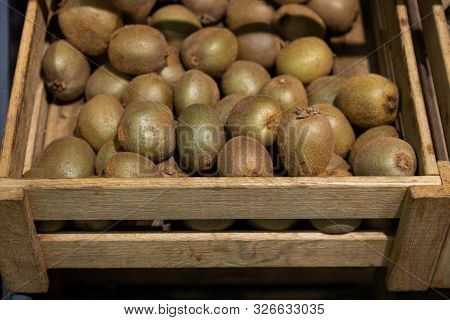 Wooden Lug Box With Ripe Kiwi Fruit On Supermarket Counter. Photo With Depth Of Field