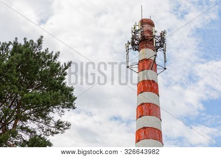 Red White Chimney With Steel Installation On Top With Tree In Blue Sky With Furry Clouds Backdrop