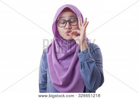 Portrait Of Beautiful Asian Muslim Woman Smiling While Making Delicious Hand Gesture With Her Finger