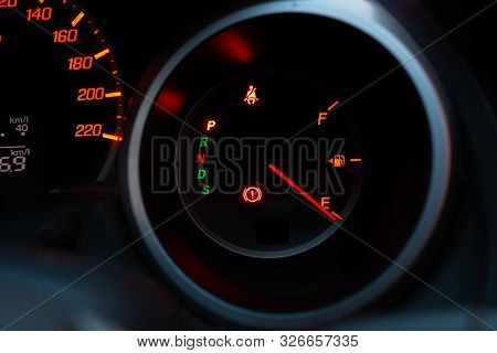 Close Up Of Meter Panel With The Needle Pointing At E On Black Blackground, Car Has Run Out Of Gas