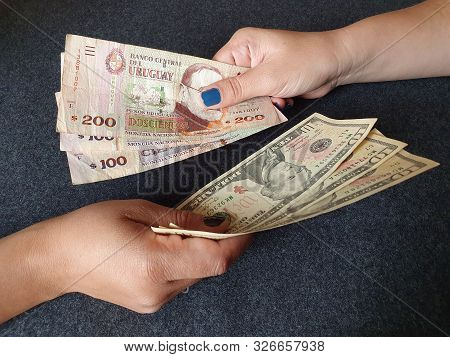 Women Hands Exchanging Uruguayan Banknotes And American Dollar Money