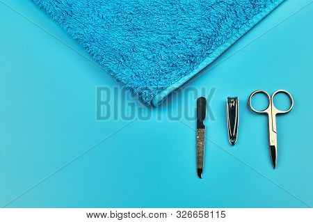 Metal Manicure Tools With Towel On Blue Background, Flat Lay With Copy Space