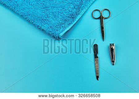 Metal Manicure Tools With Towel On Blue Background, Flat Lay With Copy Space
