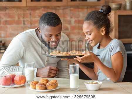 Cute Black Girl And Her Daddy Smelling Just Baked Croissants Delightfully, Father Smiling, Kitchen I
