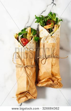 
    Fresh tortilla wraps on a marble pattern tabletop tied round with brown paper and string. Top view shot. Gourmet conception. 
