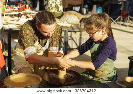 Moldavanskoye, Krymsk, Russia-05 October 2019: A Potter Teaches A Girl How To Make A Jug Of Yellow C