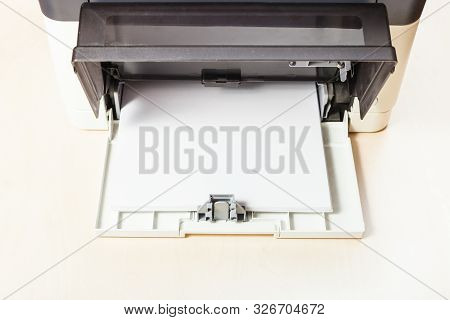 Stack Of White Paper Sheets In Printer Tray Of Multi Function Device On Table In Office