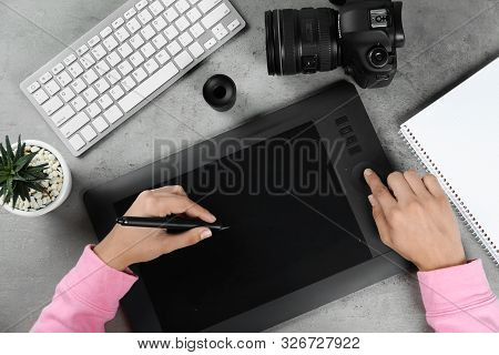 Female Designer Working With Graphic Tablet At Grey Stone Table, Top View