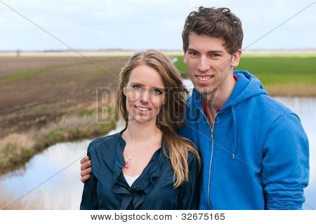 Pareja joven/esposos permanente en paisaje típico holandés