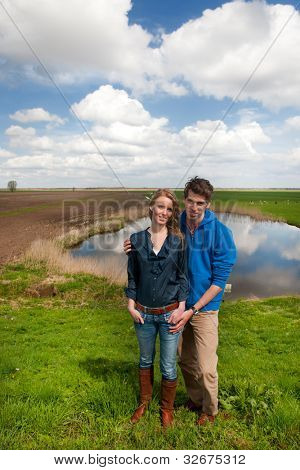 Pareja joven/esposos permanente en paisaje típico holandés