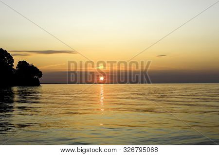 Sunset On Lake Ontario. Silhouette Of Trees Along Lakeshore At Webster, Ny