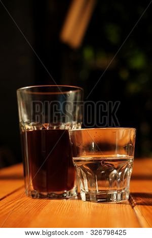 Alternative Coffee And A Glass Of Water Stand On A Wooden Table. Dark Background. Close-up