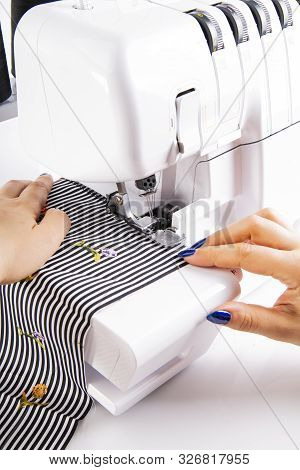 Overlock. The Woman Sews The Knit Fabric On The Overlock
