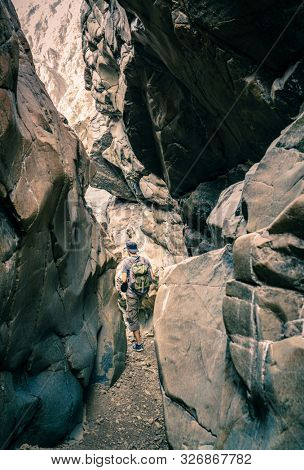 A man is hiking through a wadi in Hajar Mountains near Hatta, UAE