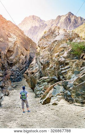A man is hiking through a wadi in Hajar Mountains near Hatta, UAE