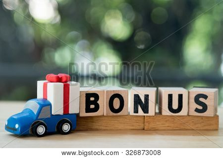 Mini Toy Truck With Gift Box Near Letter Block In Word Bonus. Yearly Bonus Concept. Bonus Is Motivat