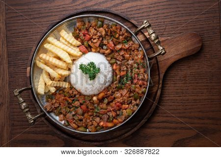 Turkish food lamb meat saute, sac kavurma with rice and french fries isolated on wooden table