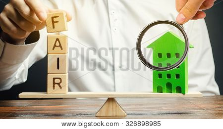 Wooden Blocks With The Word Fair And A Wooden House. Fair Value Of Real Estate And Housing. Property