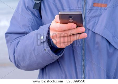 Man Typing Message On Smartphone In Coastal Town At Sea In Winter, Hands Clseup. Man Traveller Freel
