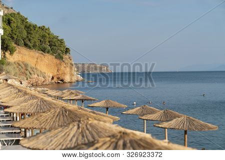 Sun Shade Umbrellas Lined Up Along Waters Edge In Summer For Beach Goers And Holiday Makers To Relax