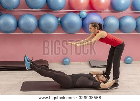 Young Man Helped By His Coach Doing Stretching Exrcises In A Gym.