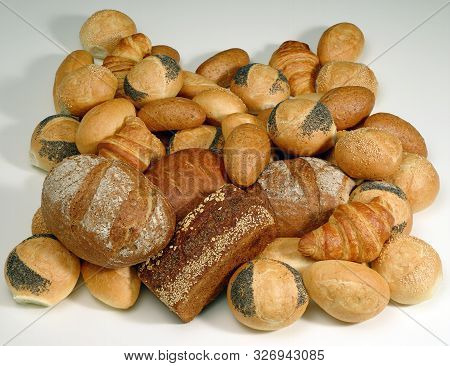 A Photograph Of A Pile Of Assorted Loaves, Rolls And Croissants Lying On A White Background